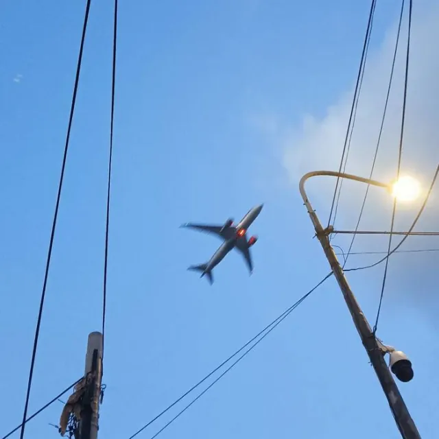 Plane over city wires